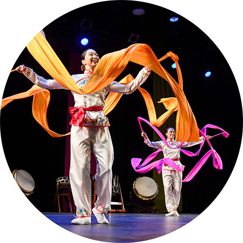 Dancers onstage performing a traditional Asian dance.