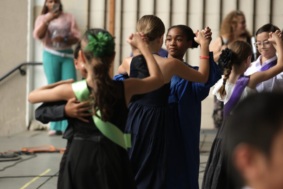 Three pairs of student dancers pose for a waltz. Their backs are to the camera.
