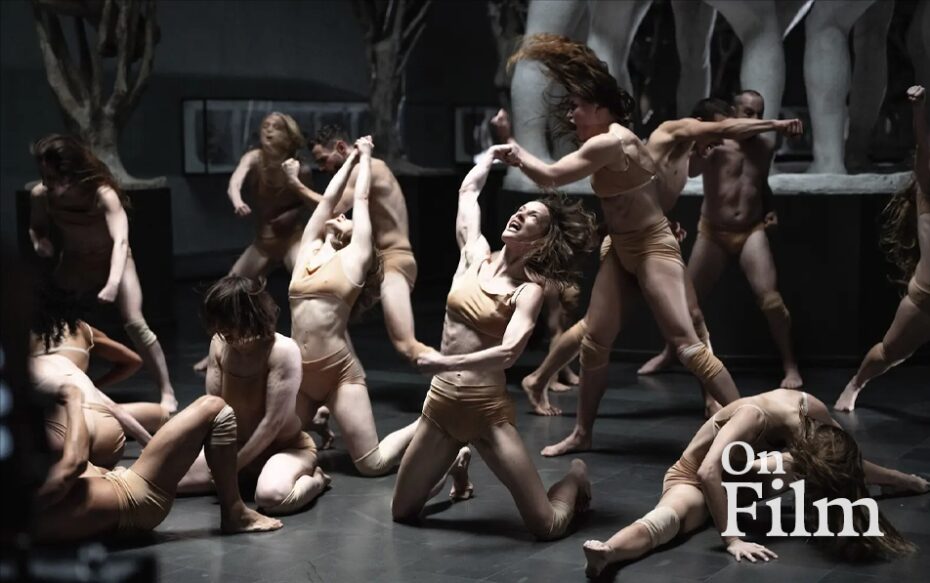 A group of dancers with their arms outstretched and interconnected.