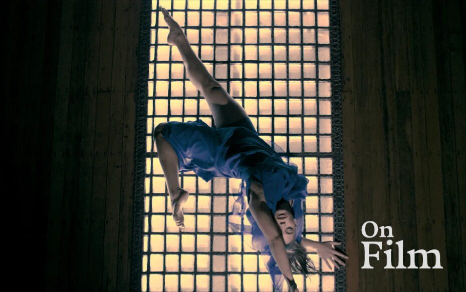 A dancer sprawled in front of a grate with light shining through.