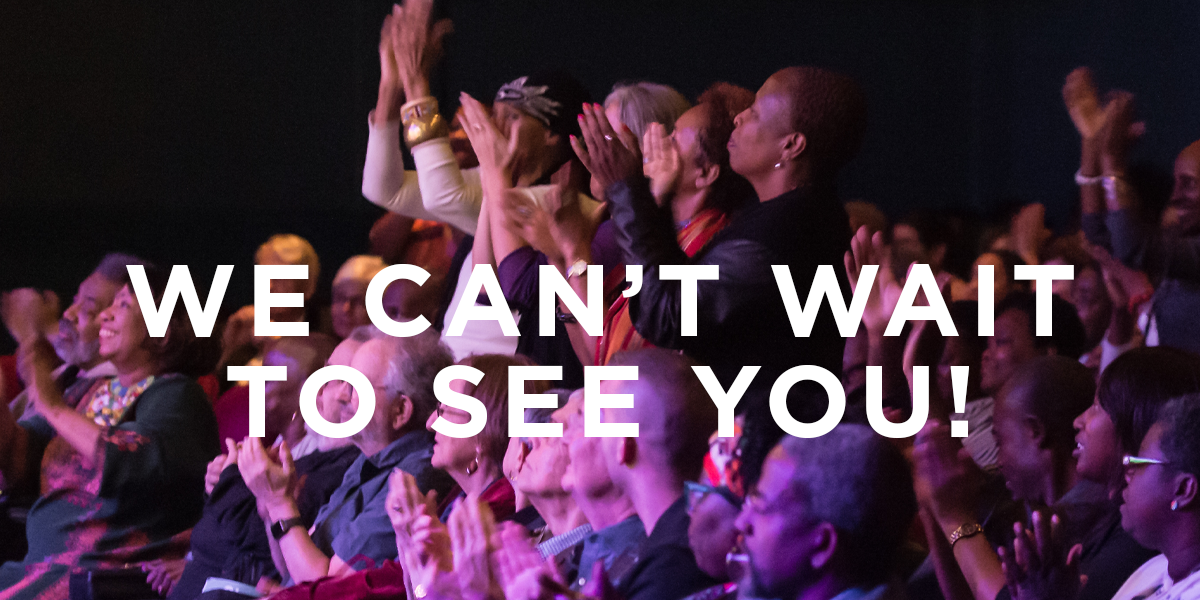 Audience stands and applauds with white text We Can't Wait to See You!