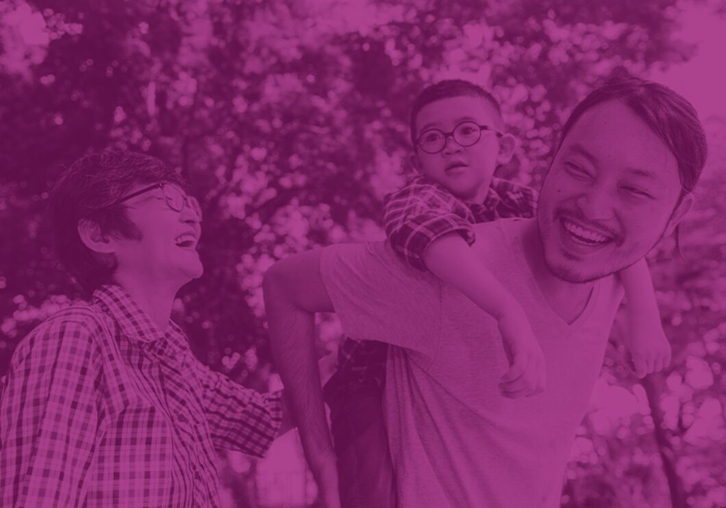 A purple-tinted image of an Asian family laughing in a park.