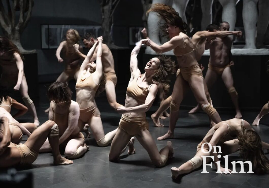 A group of dancers with their arms outstretched and interconnected.