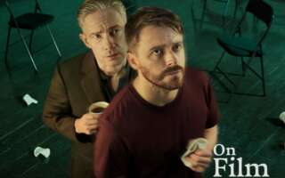 Jack Lowden and Martin Freeman in The Fifth Step. Freeman is holding a cup of coffee, and there are black folding chairs in the background.