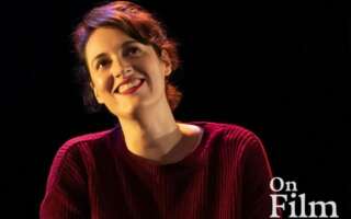 Phoebe Waller-Bridge in Fleabag, wearing a red sweater and lipstick. She is smiling.