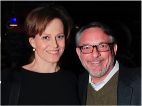 Sigourney Weaver stands next to a Symphony Space guest. Both smile.