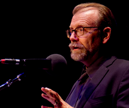 Writer George Saunders with glasses and beard talks into a mic